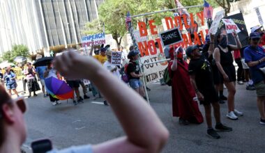 Police officers watch demonstrators marching around Pike Park to protest against President Trump and Republican leaders near the venue of the Republican convention at American Airlines Center, Thursday, Sept. 10, 2026, in Dallas.