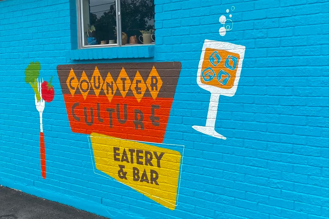 Picture shows the exterior of Counter Culture with a mural painted on a bright blue background. 