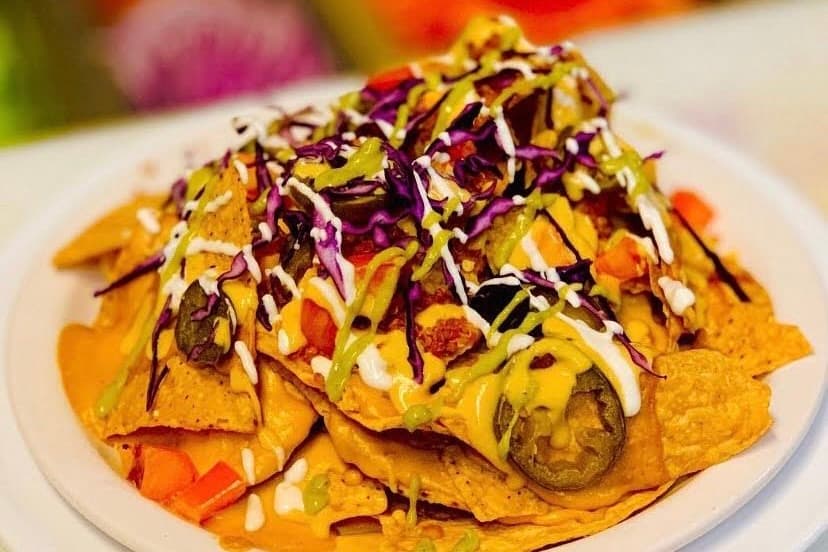 The plate shows nachos topped with sauces and purple cabbage. 