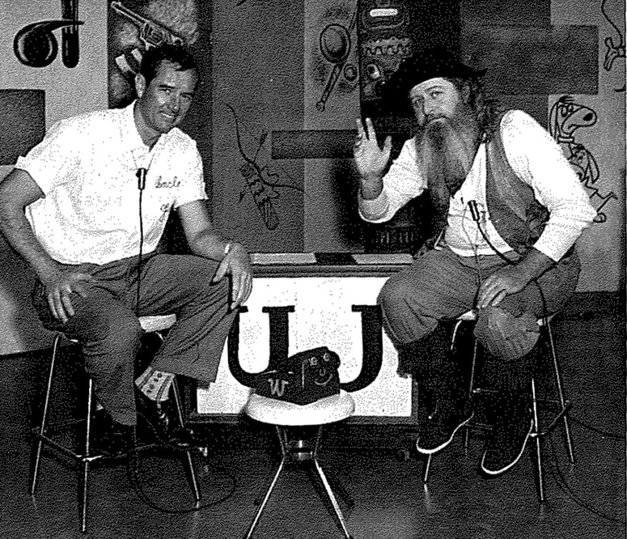 Uncle Jay and his sidekick, Packer Jack, sit on stools and pose for the camera.
