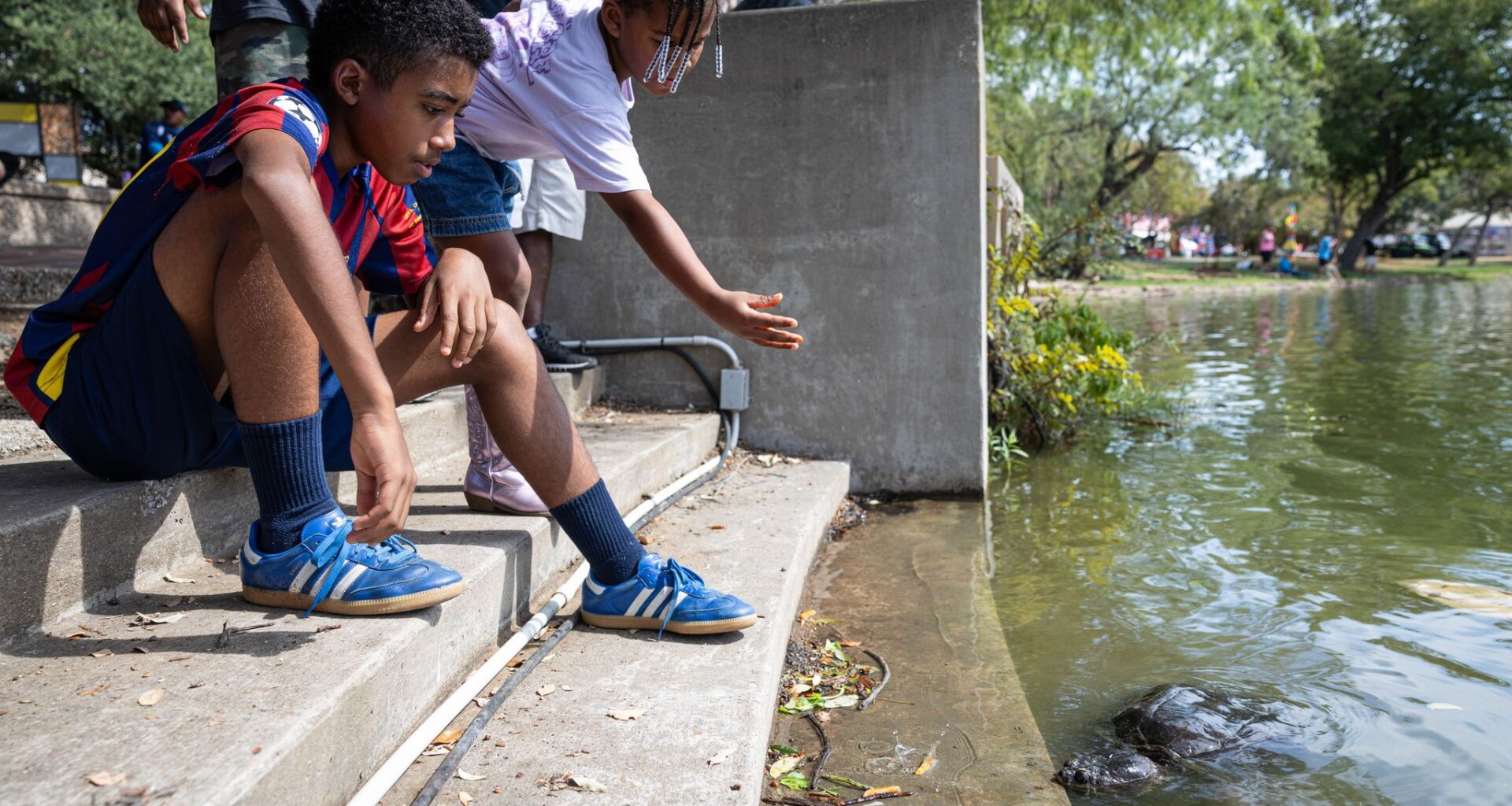 Trinity Ford and Amaan Aya feed a snapping turtle during the first day of the Texas State Fair at Fair Park in Dallas, Friday, Sept. 25, 2026.