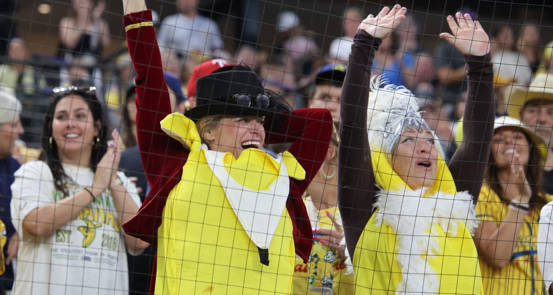 Dressed as characters from The Greatest Showman, Jennifer Hardman, left, and Kat Stevens, right, cheer early in a baseball game between Texas Tailgaters and the Savannah Bananas at Globe Life Field, Sunday Sept. 27, 2026, in Arlington