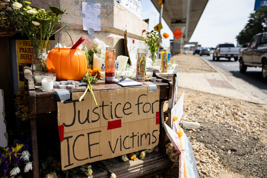 A poster on a street-side ofrenda reads “Justice for ICE victims” as traffic drives by.