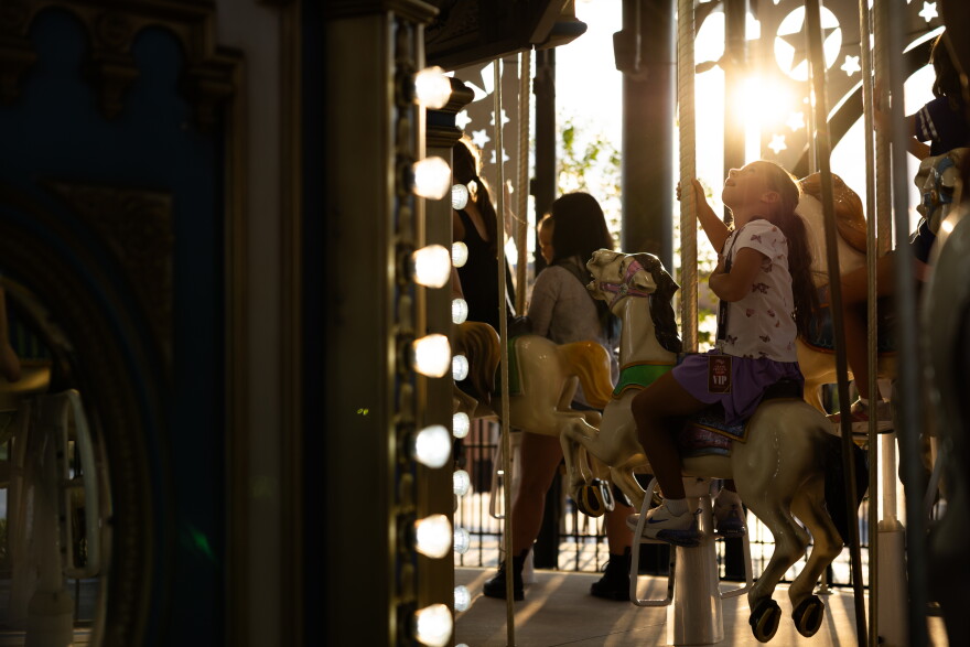 A child gazes upwards while sitting on a horse on a carousel ride.