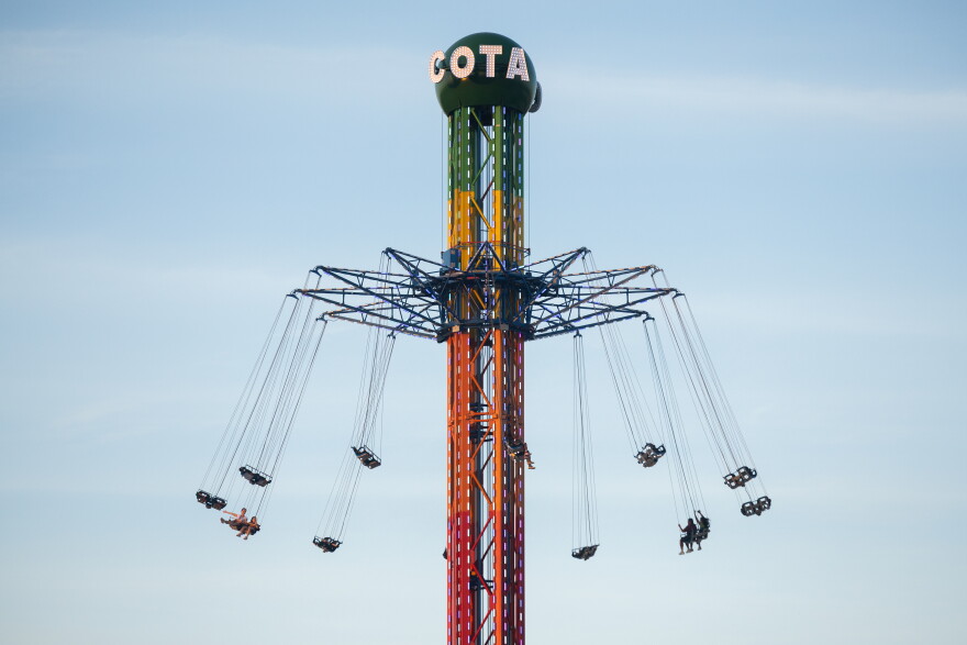 Riders sit on swings high in the air on a tower ride.