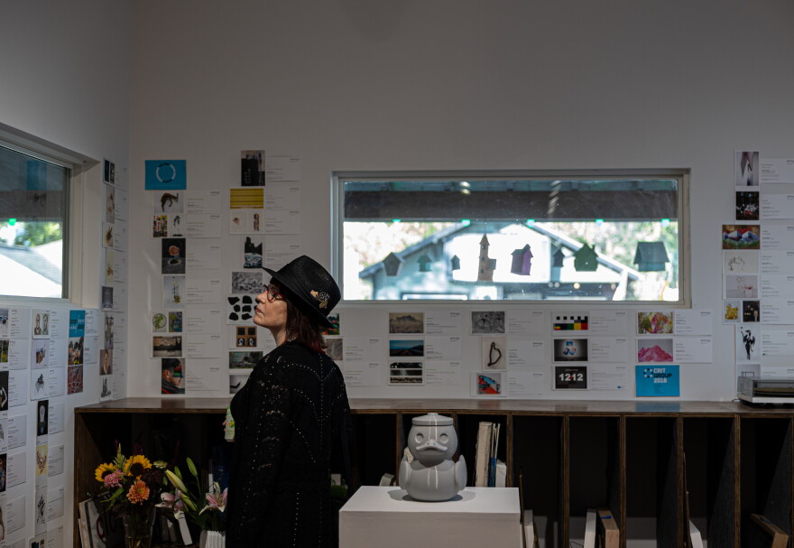 Chris Cherewan observes a postcard wall highlighting the gallery’s previous exhibits at grayDUCK gallery’s closing party in Austin, Texas on Sept. 26, 2026. Cherewan is the sister of the gallery’s owner, Jill Schroeder.