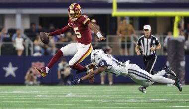 Sep 20, 2026; Arlington, Texas, USA; Washington Commanders quarterback Jayden Daniels (5) leaps to avoid a tackle by Dallas Cowboys safety Caleb Downs (13) while running with the ball during the second half at AT&T Stadium.