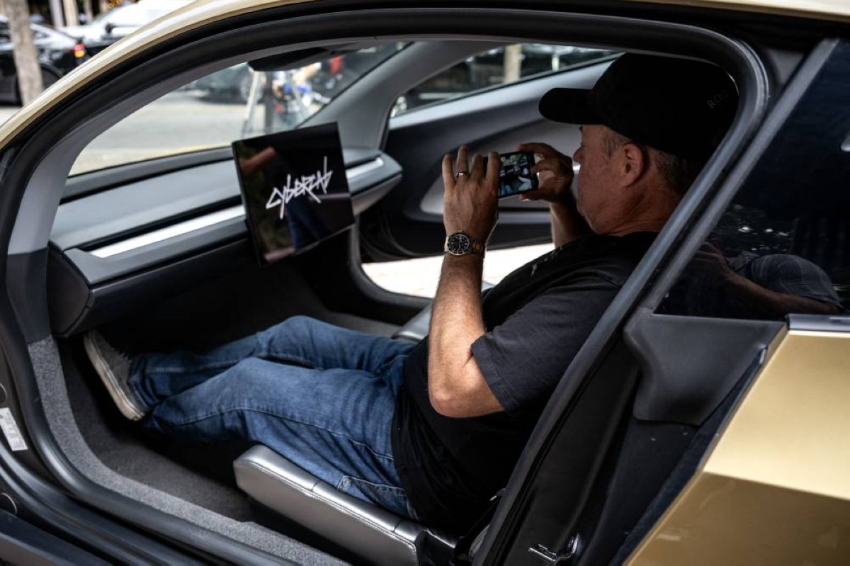 A man takes a photo inside a Tesla's "Cybercab" as it's displayed in downtown Austin, Texas, on September 3, 2026. Tesla is launching the "Cybercab" which is a taxi with no steering wheel or pedals, designed purely for autonomy. — AFP
