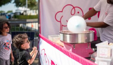 Children at fair getting cotton candy from vendor booth.
