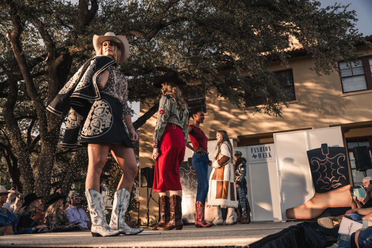 Models made their way down the runway in front of the historic Livestock Exchange Building as golden light filtered through the oaks during Fashion Week Stockyards Style. (Photo by Avin Park Photography)