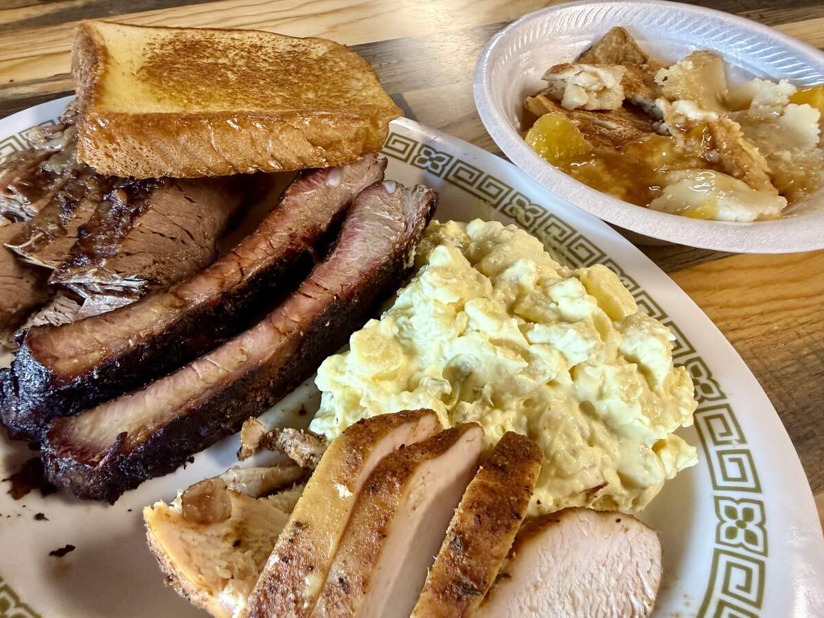 Brisket, ribs, sliced chicken breast with potato salad and peach cobbler, seen Aug. 8, 2026, at Hickory Stick Bar-B-Q in Everman, Texas.