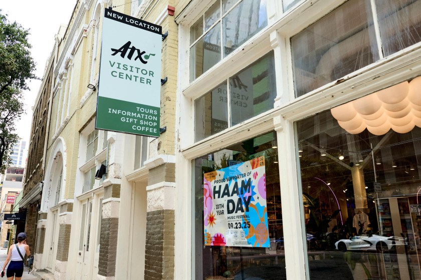 The exterior of a brick building with large windows. In the window is a colorful sign that says, "Proud Supporter of HAAM DAY Music Festival."