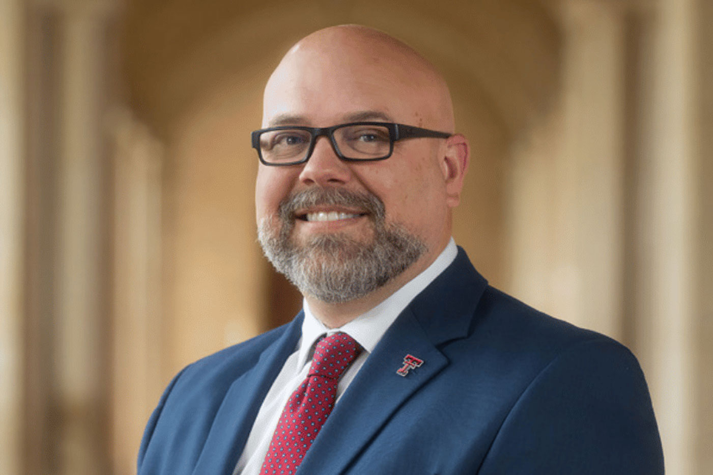 A Texas Tech provost, Rod Williams, smiles while wearing a navy suit and red tie in a professional portrait.