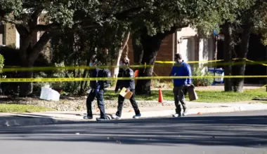 Three investigators walk in the Circle C neighborhood while wearing protective booties.