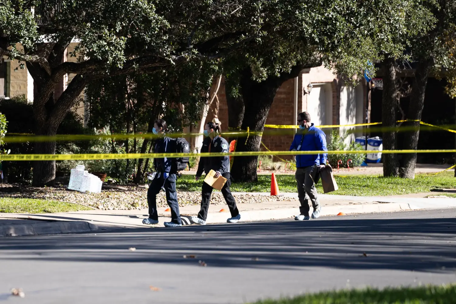 Three investigators walk in the Circle C neighborhood while wearing protective booties.
