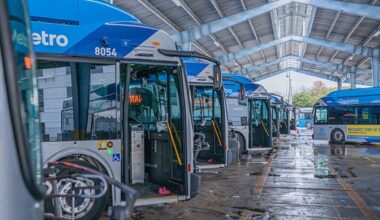 Buses parked in an indoor garage with a covered roof and wet floor.