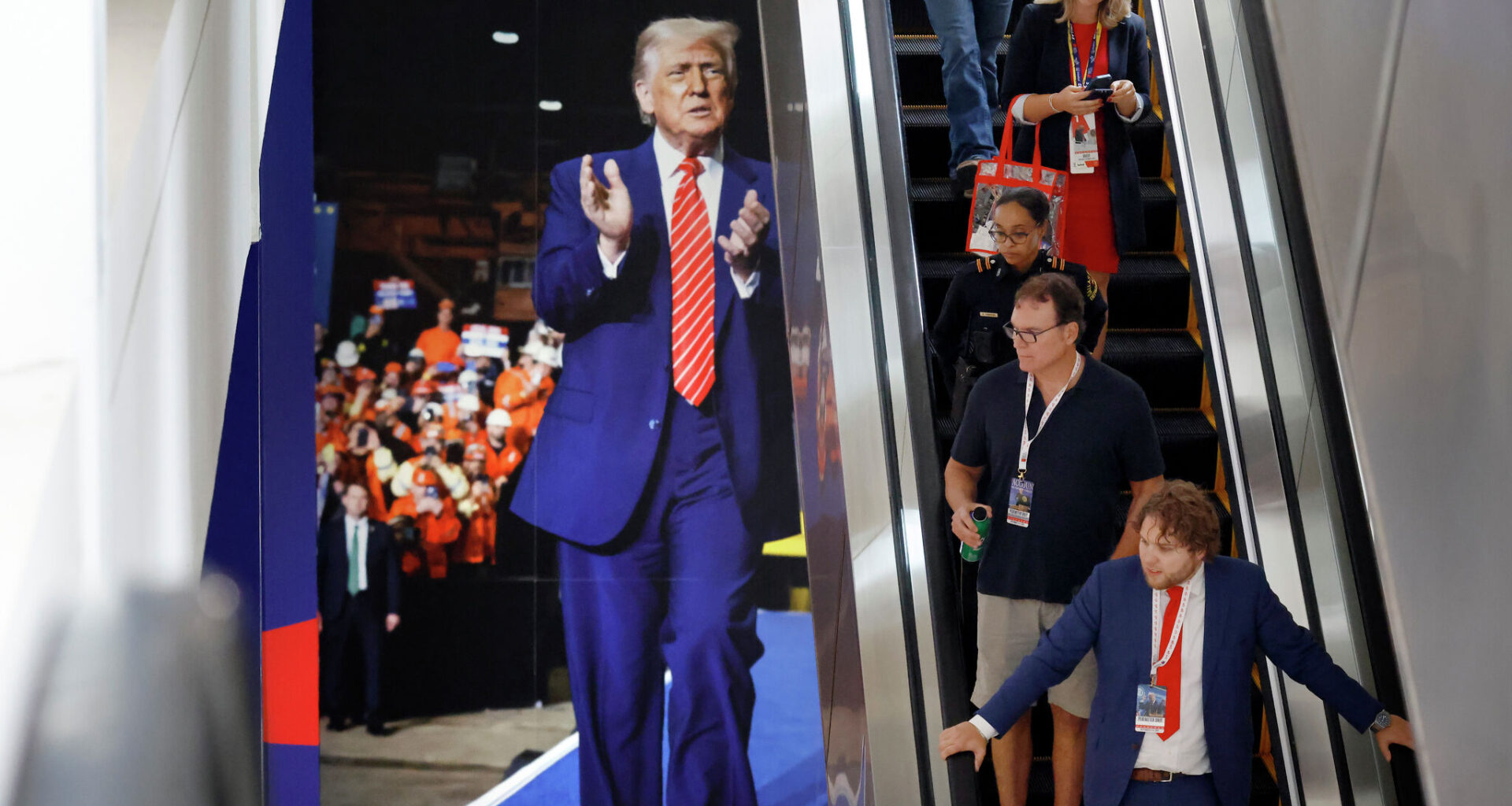 Republican midterm convention attendees take an escalator down past a large photo of President Donald Trump on Sept. 10 in the American Airlines Center.