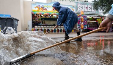 Marquist Surney and Joshua Castro, back, push water into a drain during a rainy day at the State Fair in Dallas, Thursday, Oct. 1, 2026.