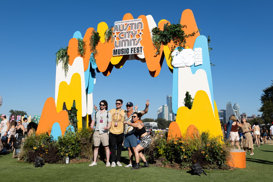 A group of people pose for a photo under an Austin City Limits Music Fest sign.