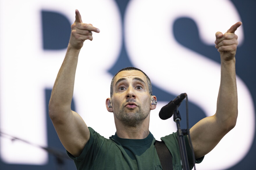 A man points his fingers in the air as he performs on stage.