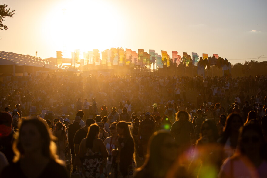 Dust particles fill the air above a large crowd as the sun sets.