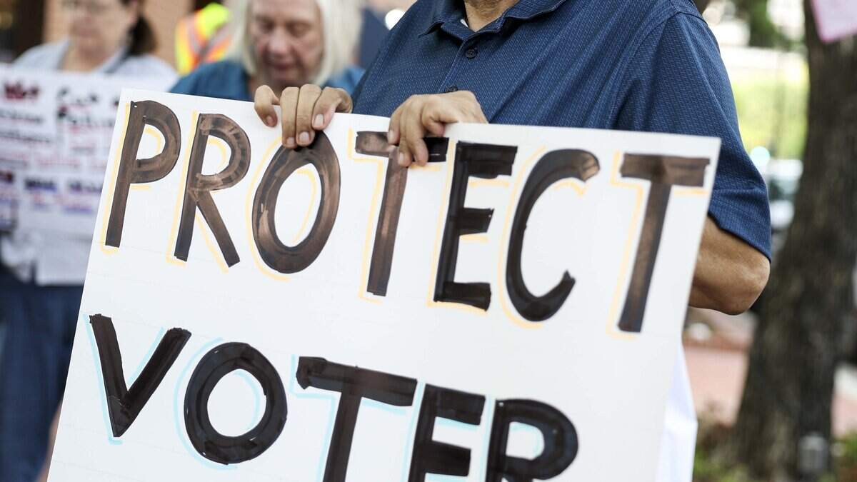 Aftab Siddiqui with the Peace and Justice Center protests outside of the Tarrant County Commissioners Court against the proposed cut of polling places on Tuesday, Aug. 4, 2026 in Fort Worth.