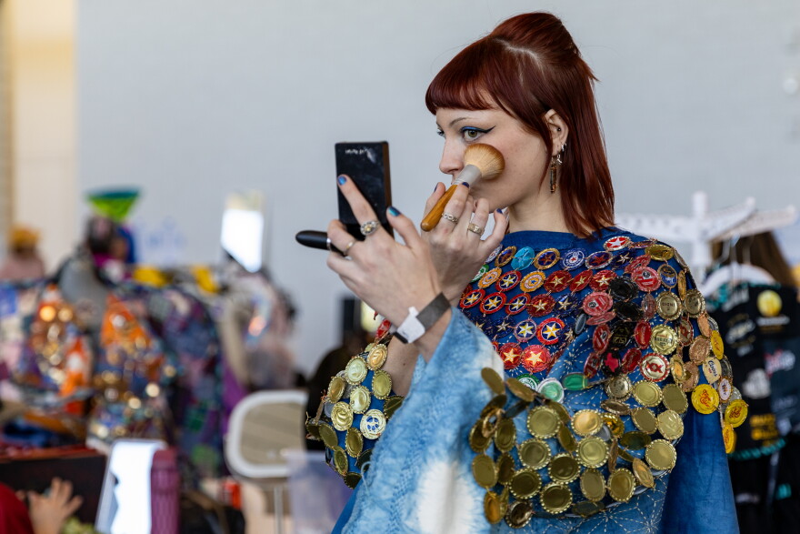 A model uses a brush to apply makeup.