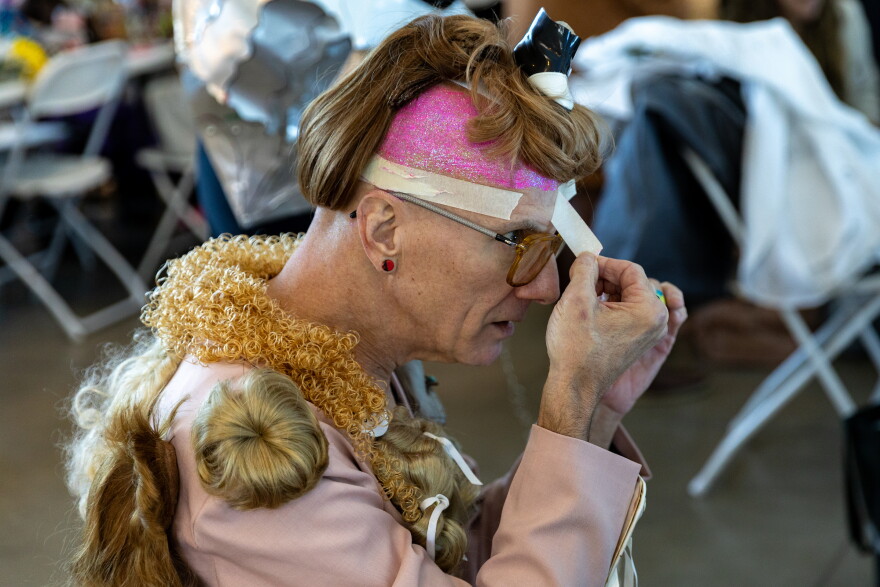 Jay Byrd removes tape around his glittered forehead backstage at the Austin Creative Reuse “Reuse on the Runway 2026” show in Austin, Texas, on Oct. 17, 2026. Joe Ferrara / KUT News