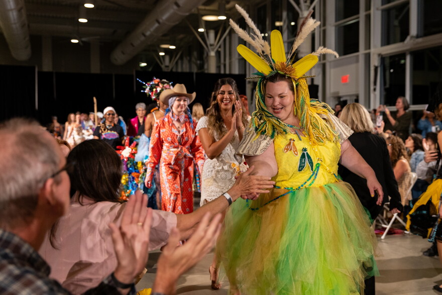 Charlotte Ellis high-fives an audience member during the final model walk at the Austin Creative Reuse “Reuse on the Runway 2026” show in Austin, Texas, on Oct. 17, 2026. Joe Ferrara / KUT News