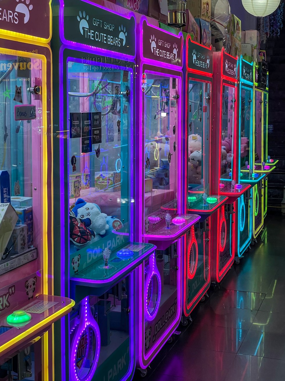 Row of colorful arcade claw machines with prizes