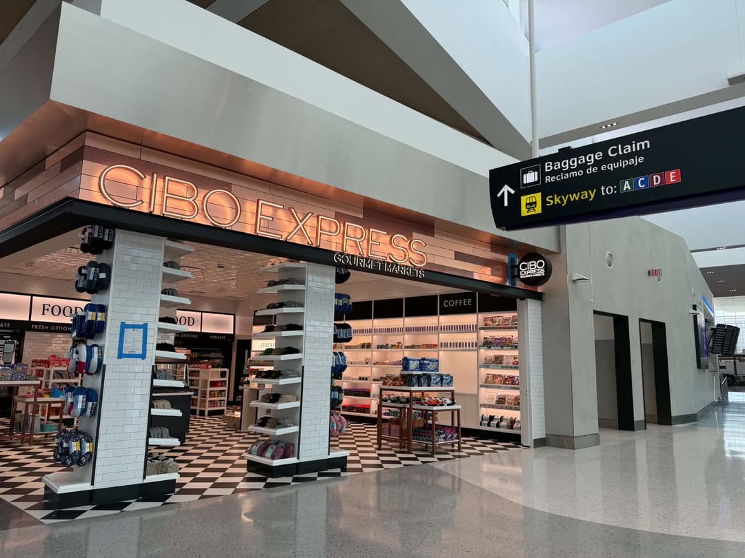CIBO Express Gourmet Market store in airport terminal beside Baggage Claim and Skyway directional sign.