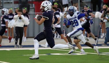 Navy-clad football player with the ball runs toward the end zone as a blue-and-white defender chases him.
