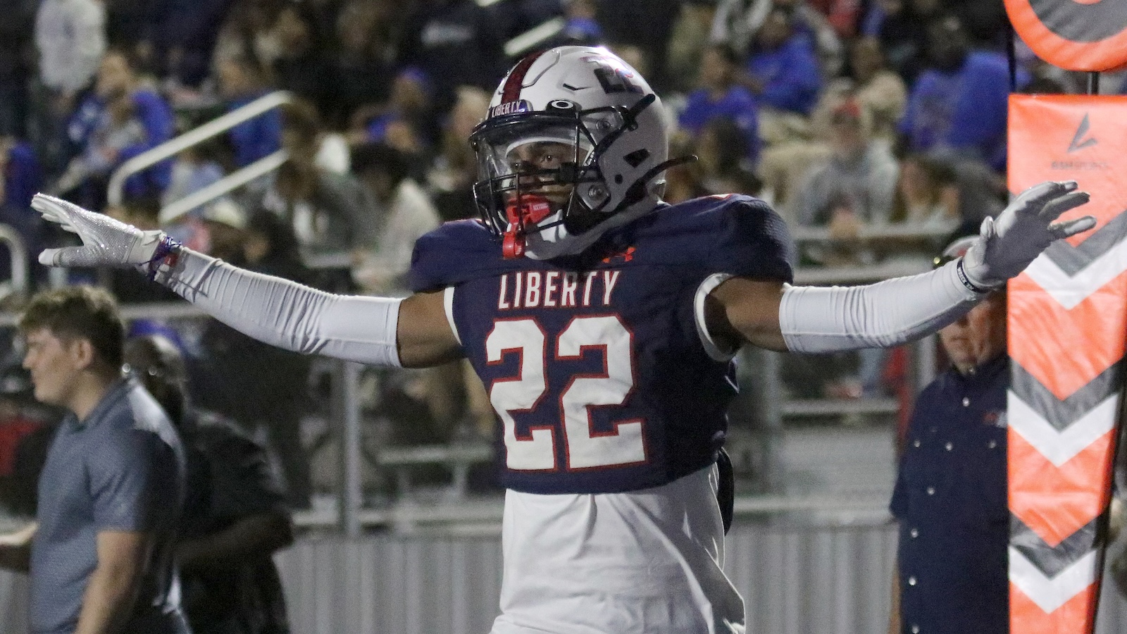 Liberty football player wearing #22 jersey with arms outstretched in celebration near the sideline.
