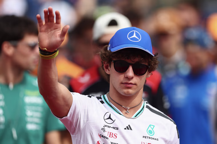 Andrea Kimi Antonelli waves while wearing a blue Mercedes cap and sunglasses.
