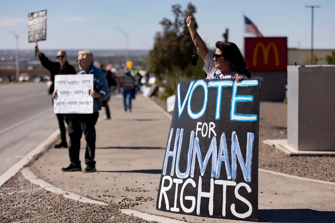 A participant raises a fist while holding a “Vote for human rights” sign along Eastlake Boulevard during a “No Kings” sidewalk protest organized by Indivisible the 915 in El Paso, Texas, on Saturday, Oct. 17, 2026.