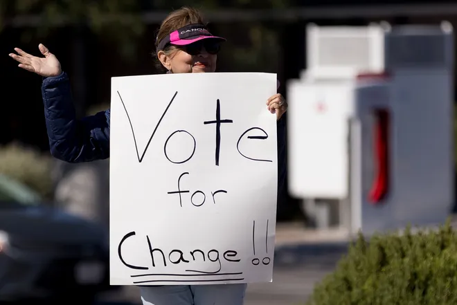 A participant waves while holding a “Vote for change” sign along Eastlake Boulevard during a “No Kings” sidewalk protest organized by Indivisible the 915 in El Paso, Texas, on Saturday, Oct. 17, 2026.