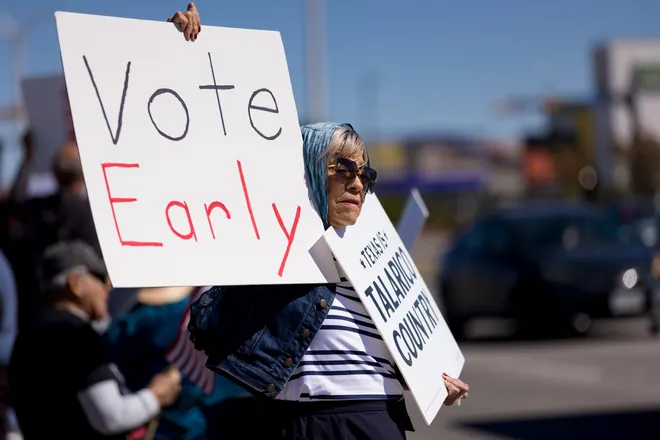 A participant holds “Vote early” and “Texas is Talarico country” signs along Eastlake Boulevard during a “No Kings” sidewalk protest organized by Indivisible the 915 in El Paso, Texas, on Saturday, Oct. 17, 2026.