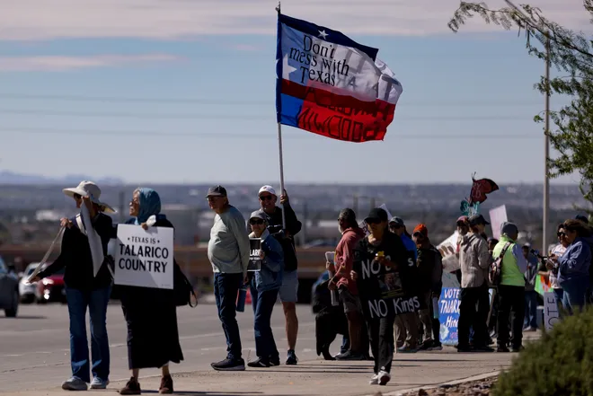 Participants display signs and a flag along Eastlake Boulevard during a “No Kings” sidewalk protest organized by Indivisible the 915 in El Paso, Texas, on Saturday, Oct. 17, 2026.