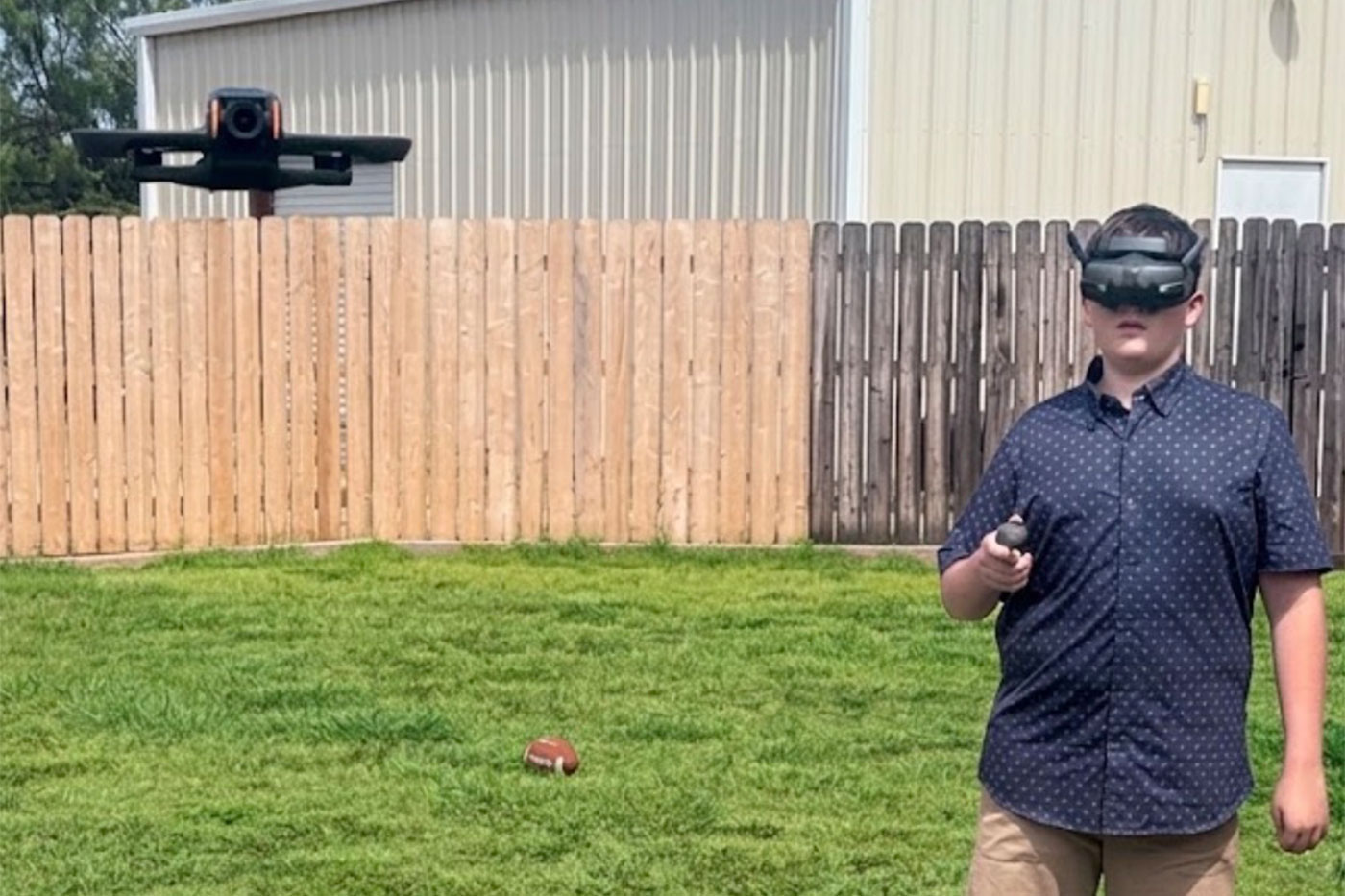 Ty stands in his backyard flying a drone, wearing first-person-view drone goggles.