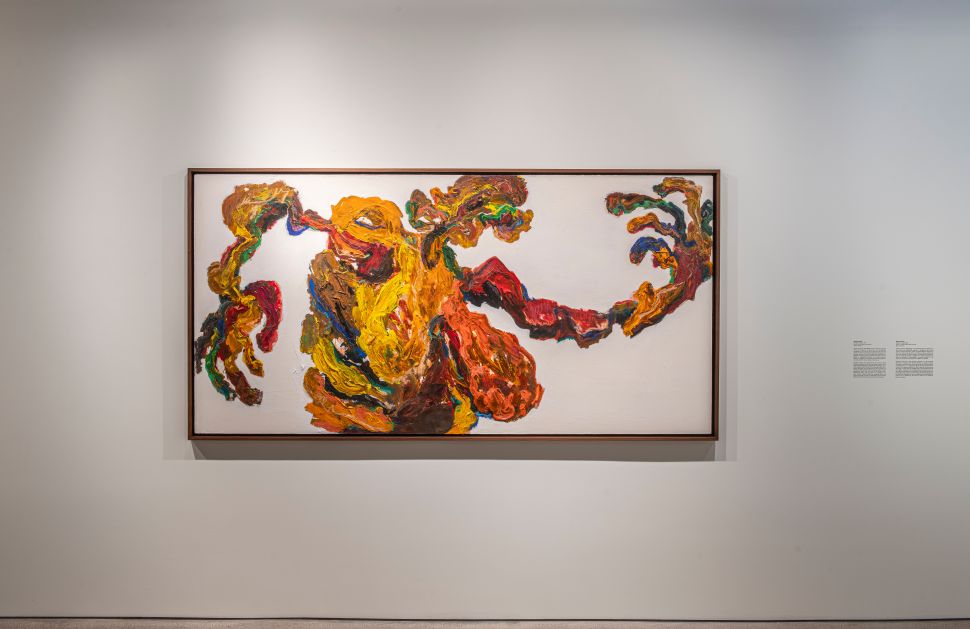 A large, vividly colored abstract painting in orange, yellow, red and green dominates a white gallery wall at Ostillo Art Foundation.