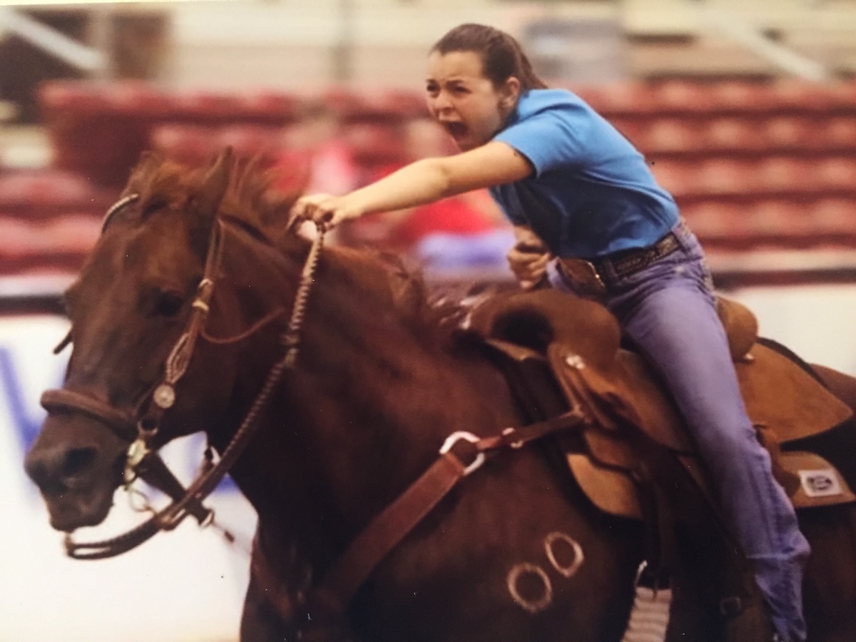 A middle school aged girl on a horse races barrels