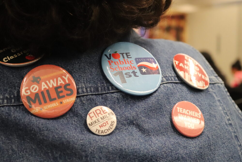 An attendee to the Houston ISD School Board meeting wears buttons advocating for the end of the takeover. August 2026.