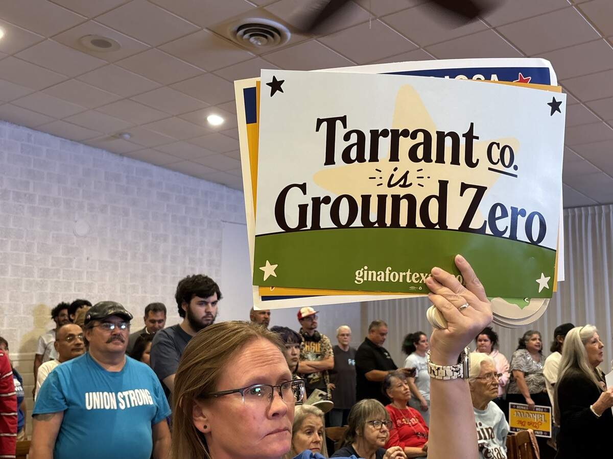 A Tarrant County resident and Gina Hinojosa supporter raises a political sign reading “Tarrant County is ground zero” at a Hinojosa rally on Oct. 27, 2026 at the National Hall SPJST Lodge 92 in Lake Worth.