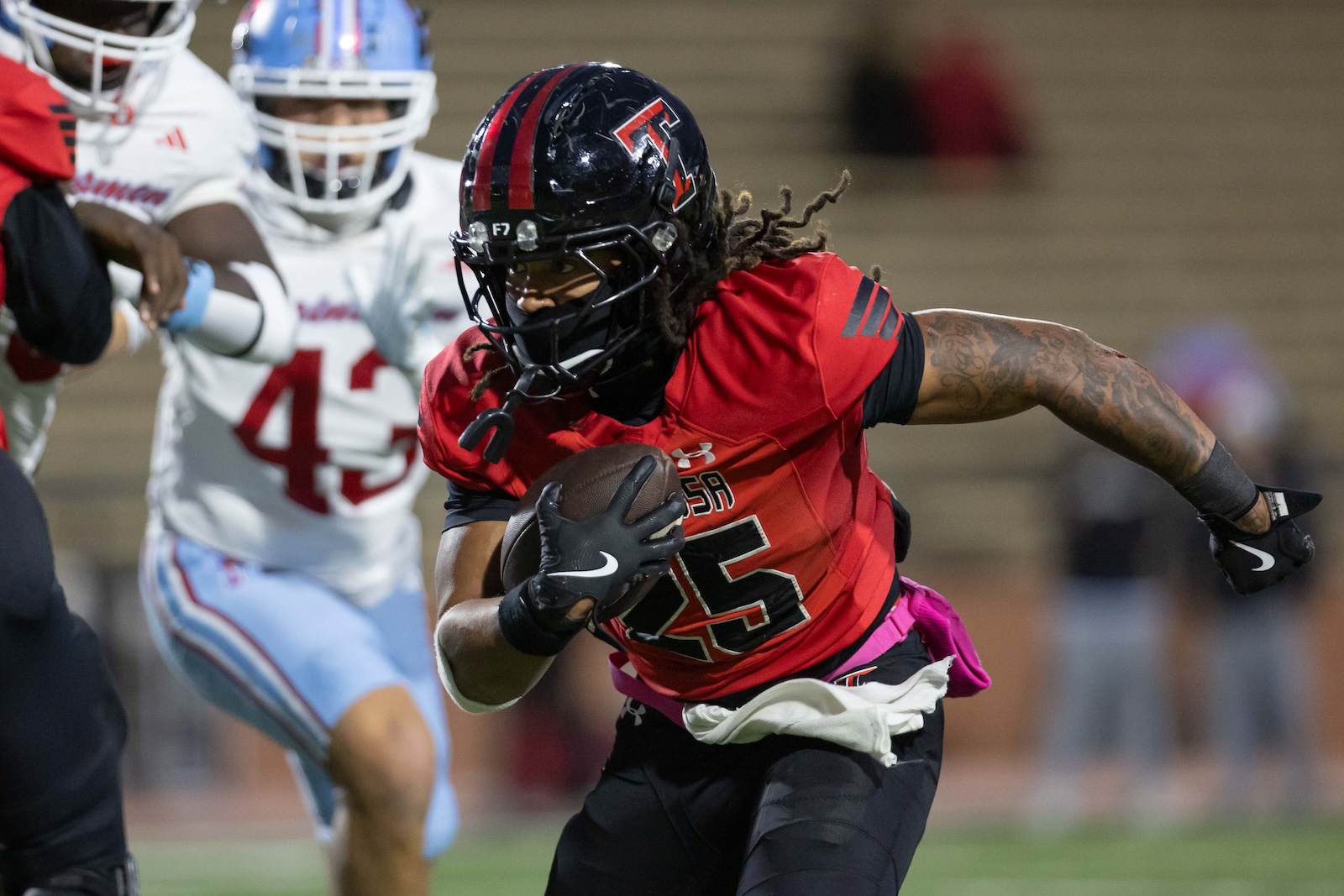 MHS-THS-FB-14 | Press Pass Sports Football player in a red jersey runs with the ball during a game, black helmet and gloves visible.