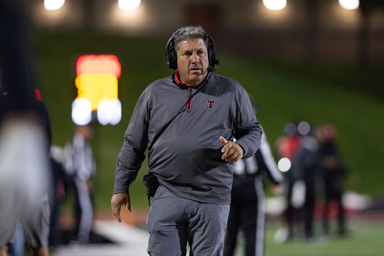 MHS-THS-FB-18 | Press Pass Sports Coach wearing a headset and gray pullover on the football sideline during a night game.