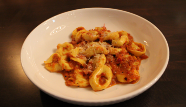A bowl of Sorella's tortellini alla niavola, with a bright red chili sauce and grated parmigiano reggiano
