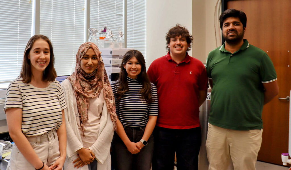 A group photo of five people in a classroom setting.