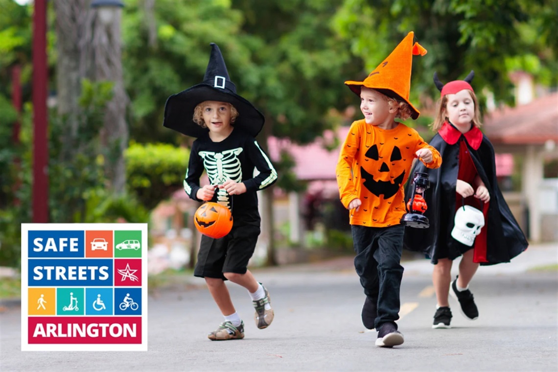 Children in Halloween costumes carrying candy buckets while walking down a street. Safe Streets Arlington logo