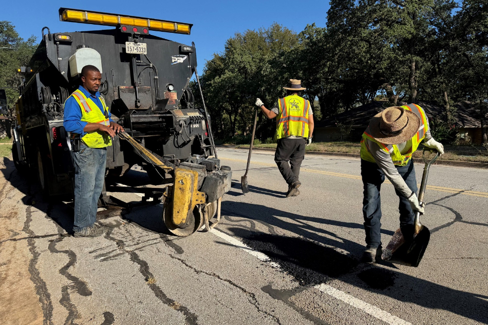 Three City of Arlington Public Works employees in safety vests repair a pothole on Washington Drive in North Arlington.