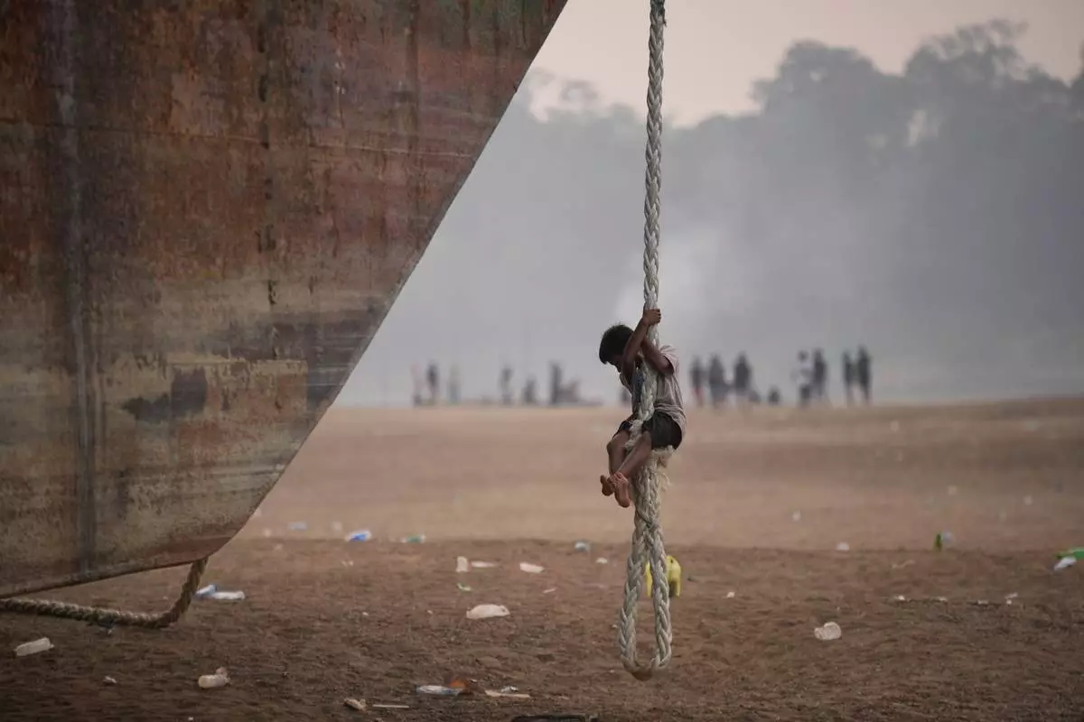 A boy climbs a rope hanging from a barge stranded on a dry riverbed of the Kapuas River amid a drought in Sekadau, West Kalimantan, Indonesia, Friday, Sept. 11, 2026. (AP Photo/Tatan Syuflana)